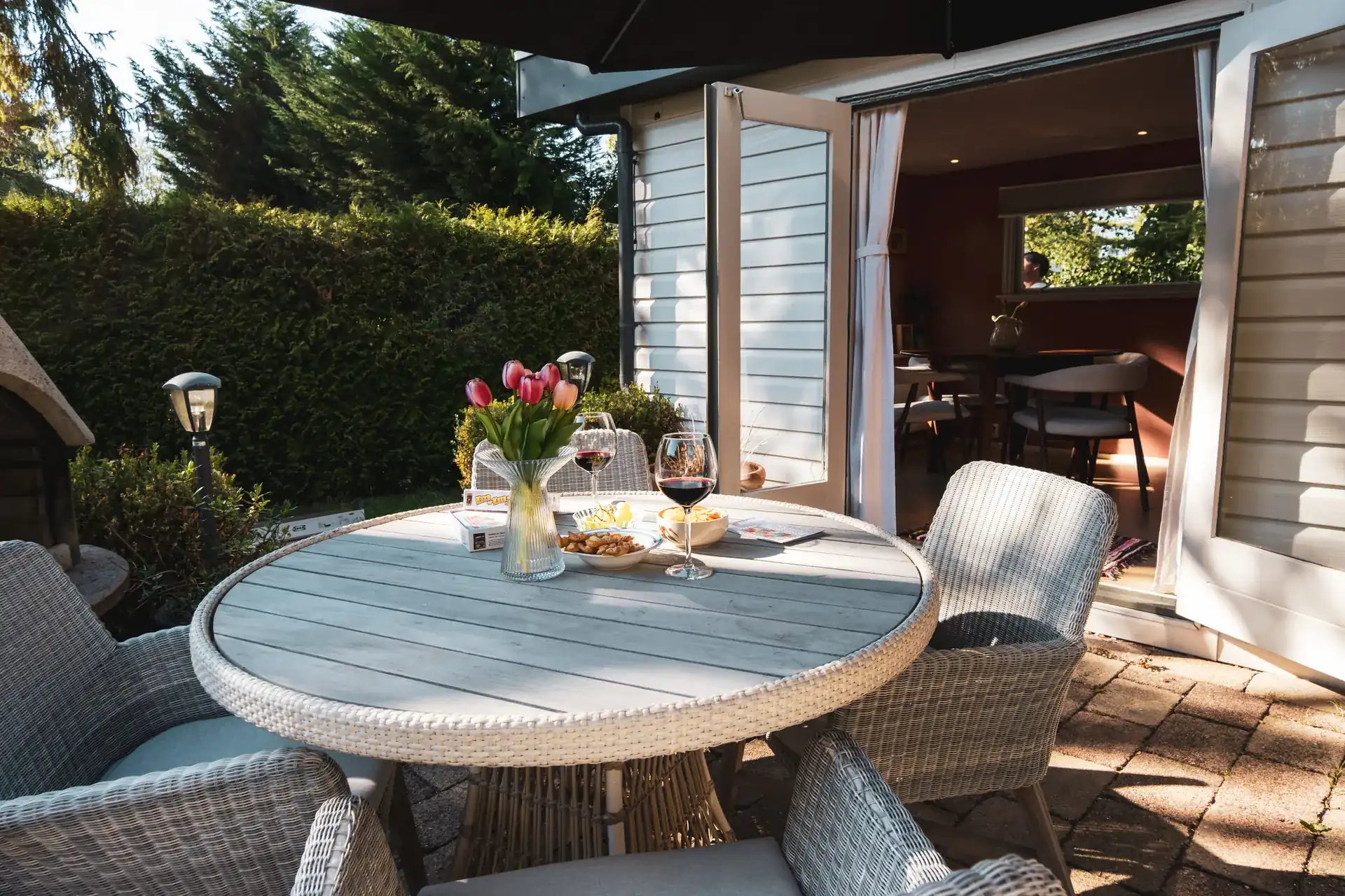 Terras met ronde tuintafel aan de openslaande deuren van Huisje Pip op de Veluwe