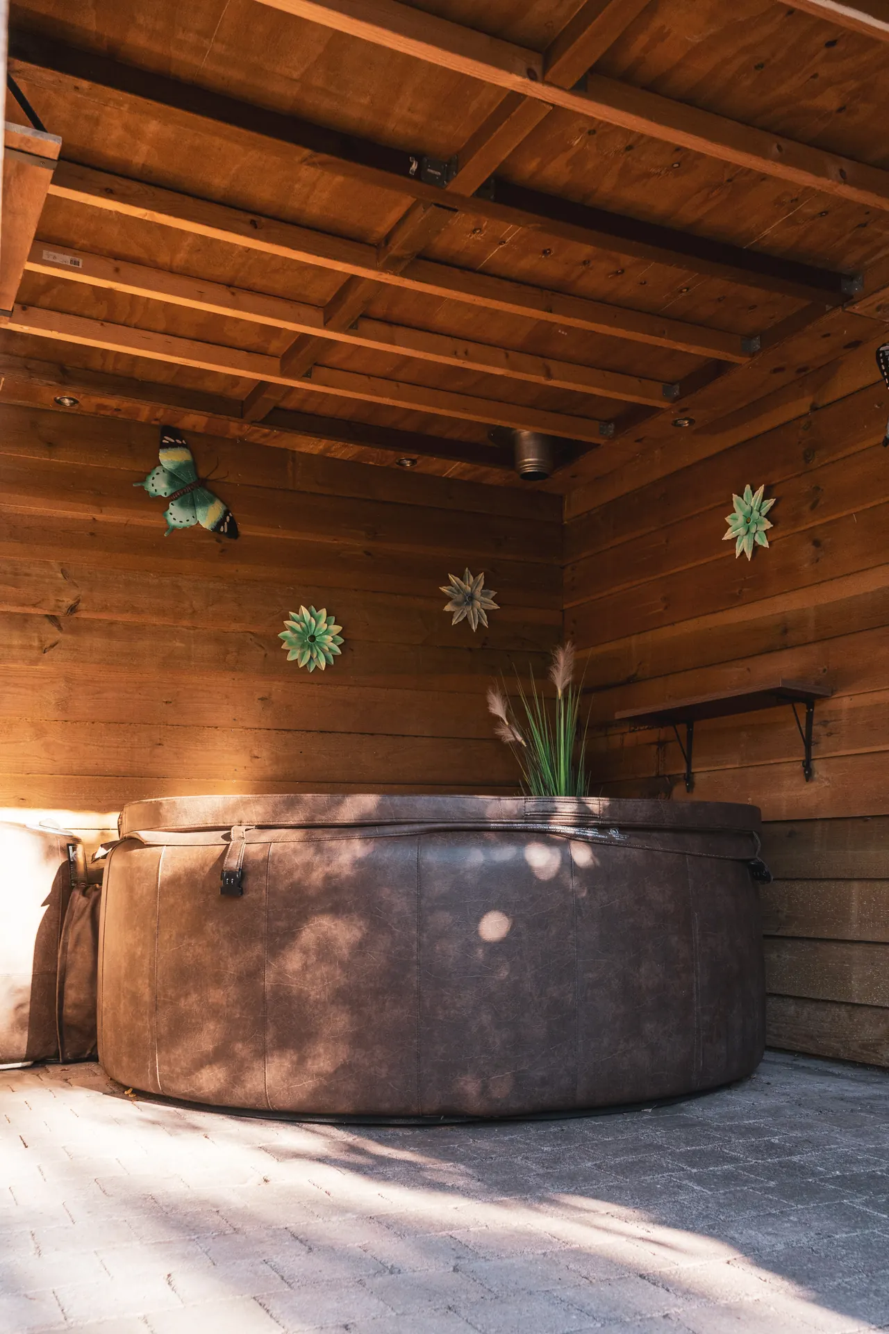 Jacuzzi overdag onder de houten overkapping in de tuin van Huisje Pip